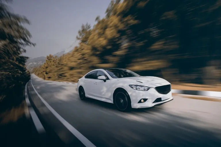 Voiture blanche sportive sur route sinueuse, performance et vitesse avec as-rocauto81 dans le Tarn